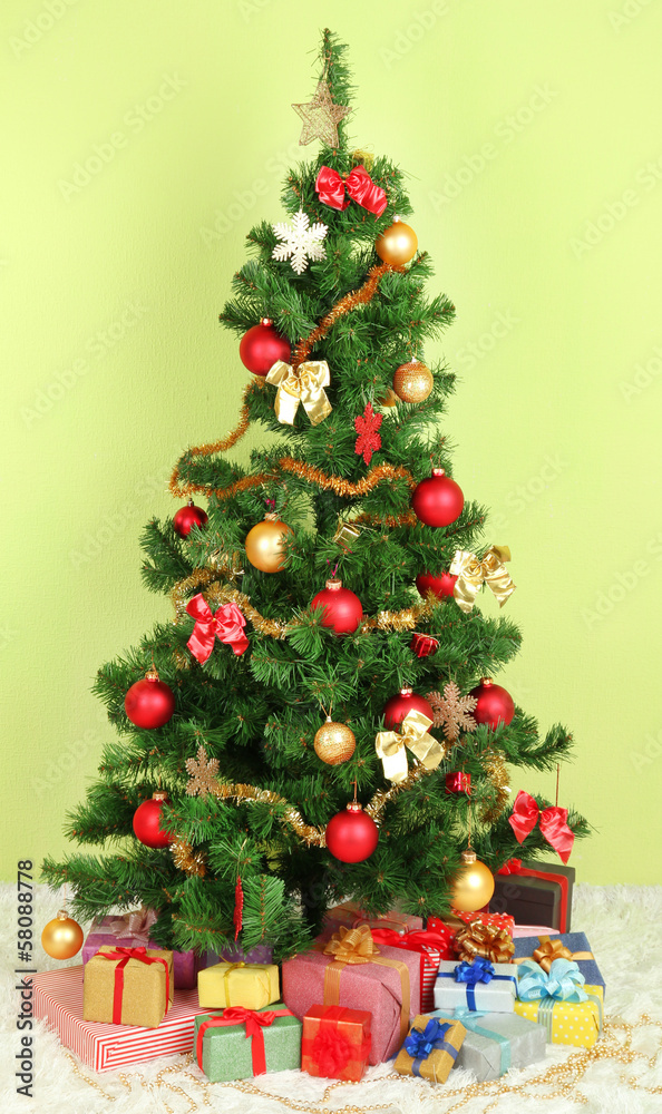 Decorated Christmas tree with gifts on green wall background