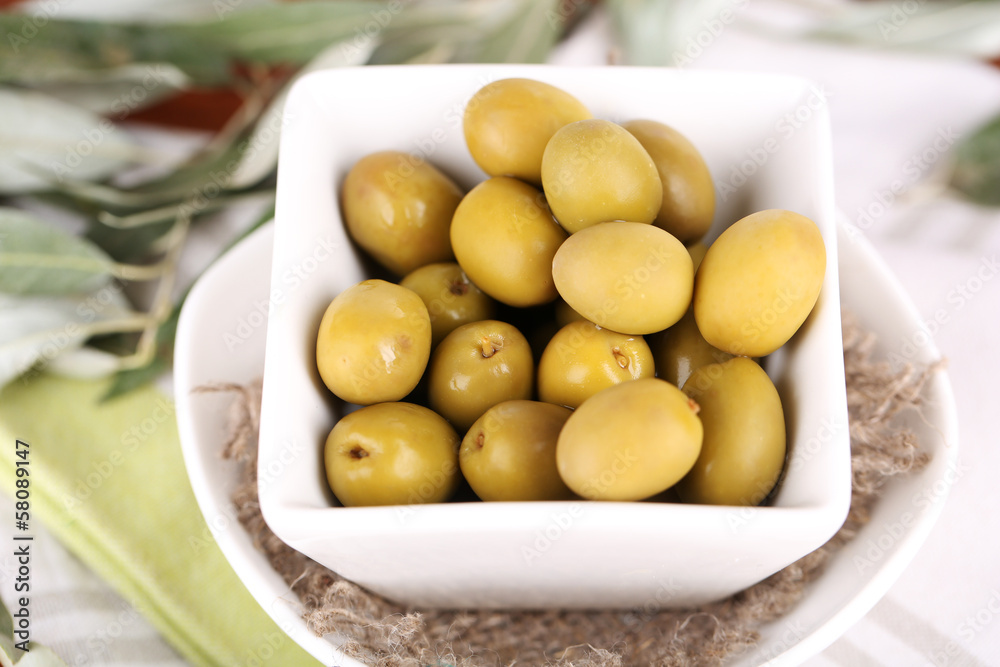 Olives in bowl with branch on napkin close-up Olives in bowl with branch on napkin close-up