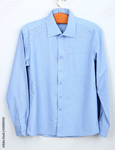 Male shirt on wooden hanger on wall background