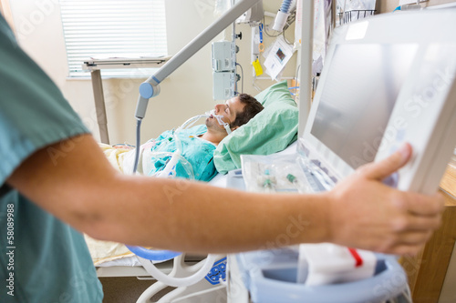 Bild auf Leinwand Nurse Pressing Monitor's Button With Patient Lying On Bed