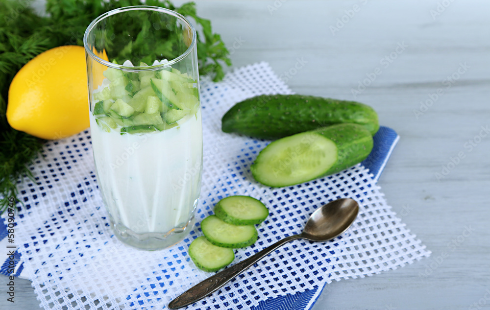 Cucumber yogurt in glass, on color napkin, on wooden Cucumber yogurt in glass, on color napkin, on wooden