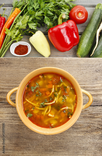 Top view on pot of tomato soup and fresh vegetables on old wood