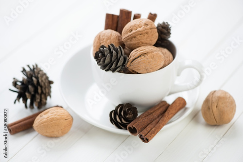 Walnuts  cinnamon and fir-cones  white wooden background