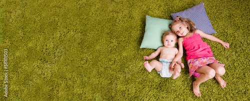 Obraz na płótnie Two happy sisters lie on carpet w salonie