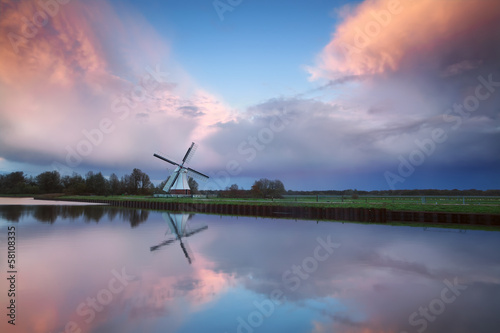 beautiful sunset over Dutch windmill by river