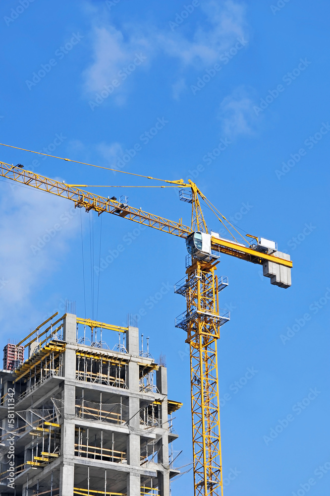 Crane and building construction site against blue sky Crane and building construction site against blue sky
