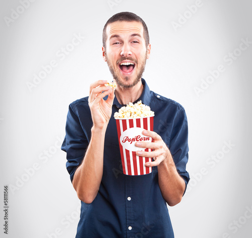 Young happy man watching movie and holding popcorn