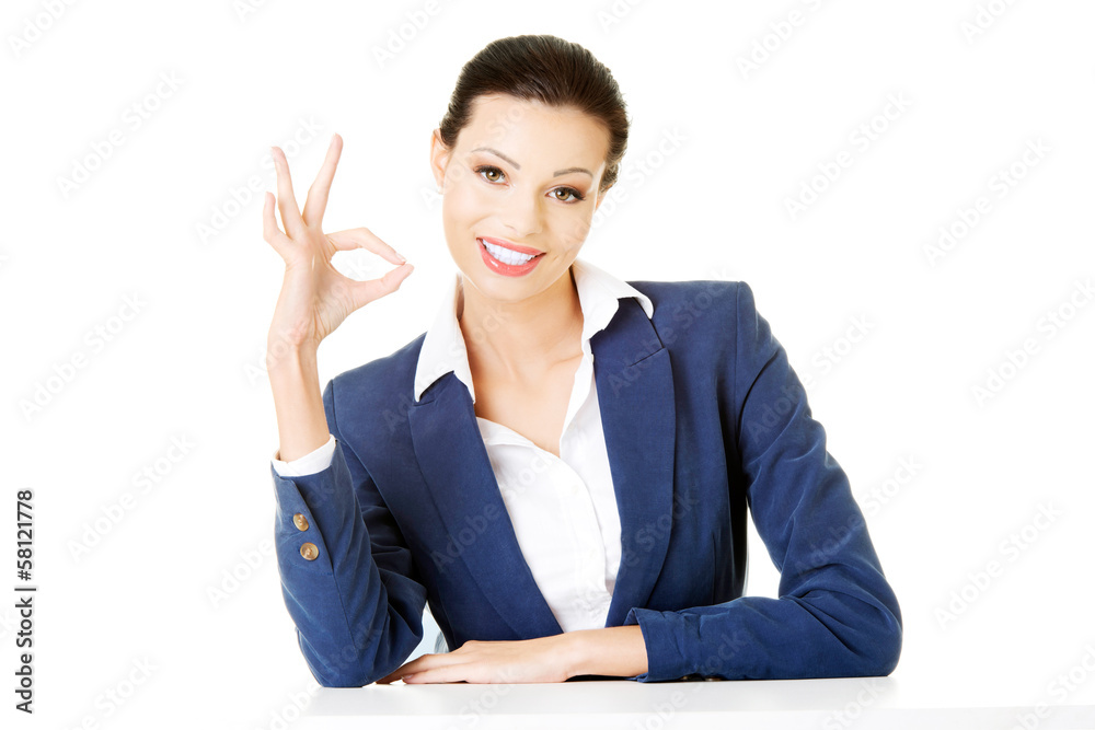 Attractive business woman showing OK and sitting. Attractive business woman showing OK and sitting.