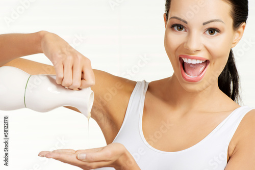 Attractive woman spilling oil on hand.
