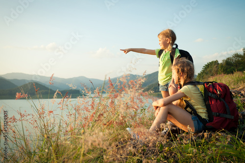 Fotografie two little girls watching the sunset on the lake