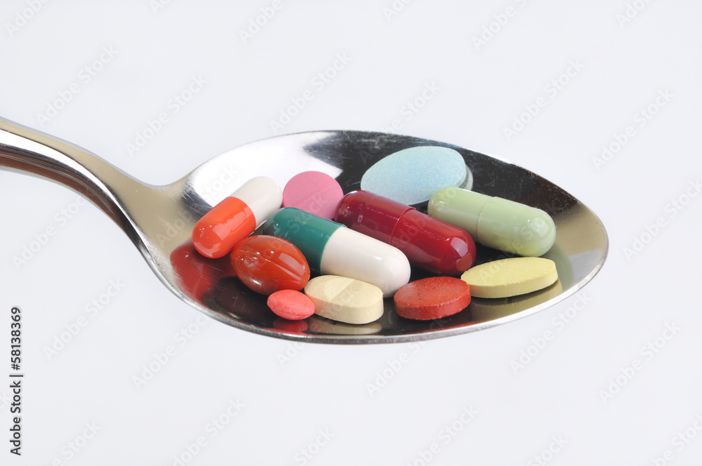 Many different colored tablets and pills on a spoon isolated in Many different colored tablets and pills on a spoon isolated in