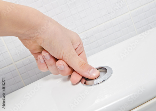 finger pushing button and flushing toilet photo