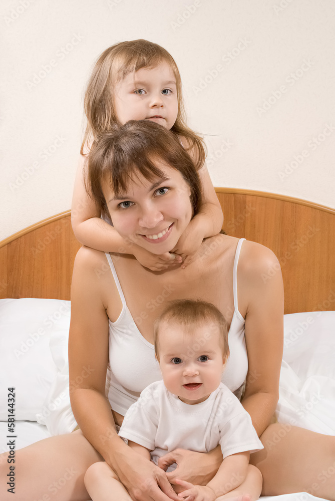 Mother and children playing and smiling on the bed at home Mother and children playing and smiling on the bed at home