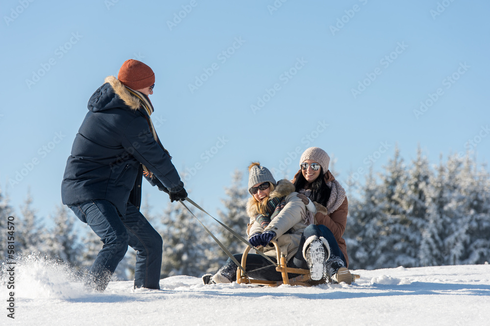 © CandyBox Images - Young man pulling girls on winter sledge © CandyBox Images - Young man pulling girls on winter sledge
