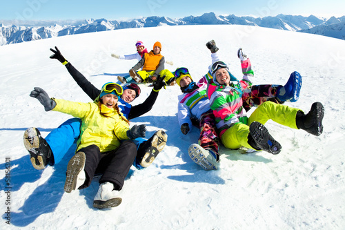 friends slide downhill together on mountain holiday