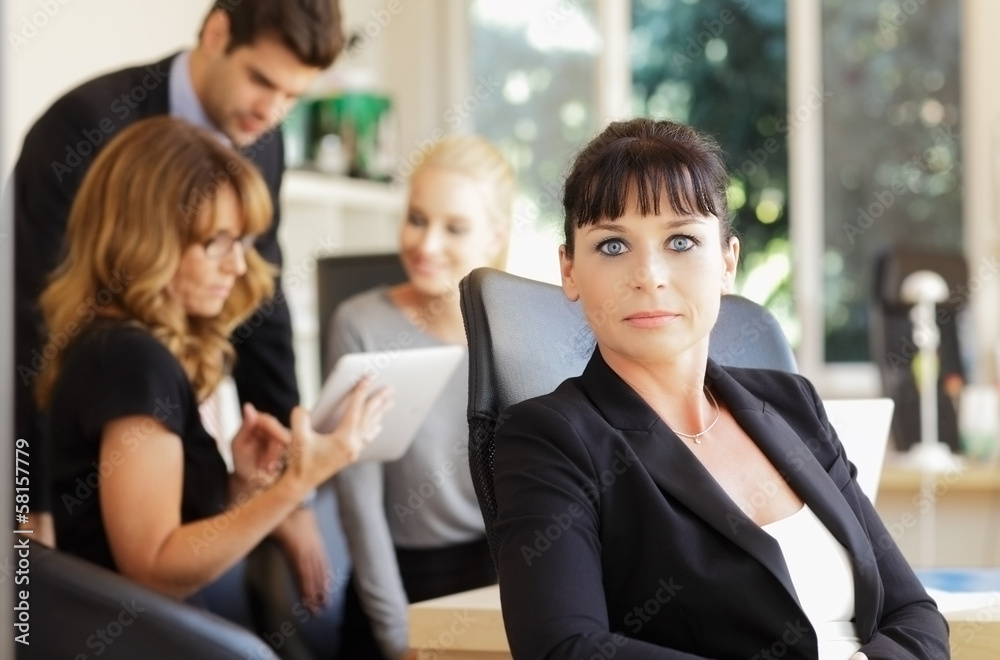 Happy businesswoman with colleagues in the background