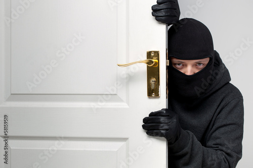 Burglar sneaking in a open house door photo