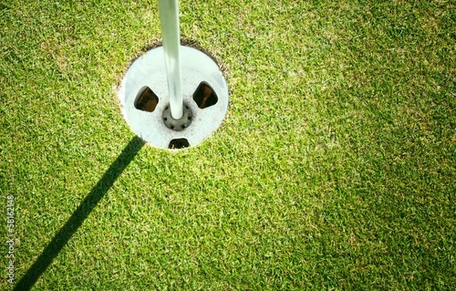 Golf cup on green background with copyspace