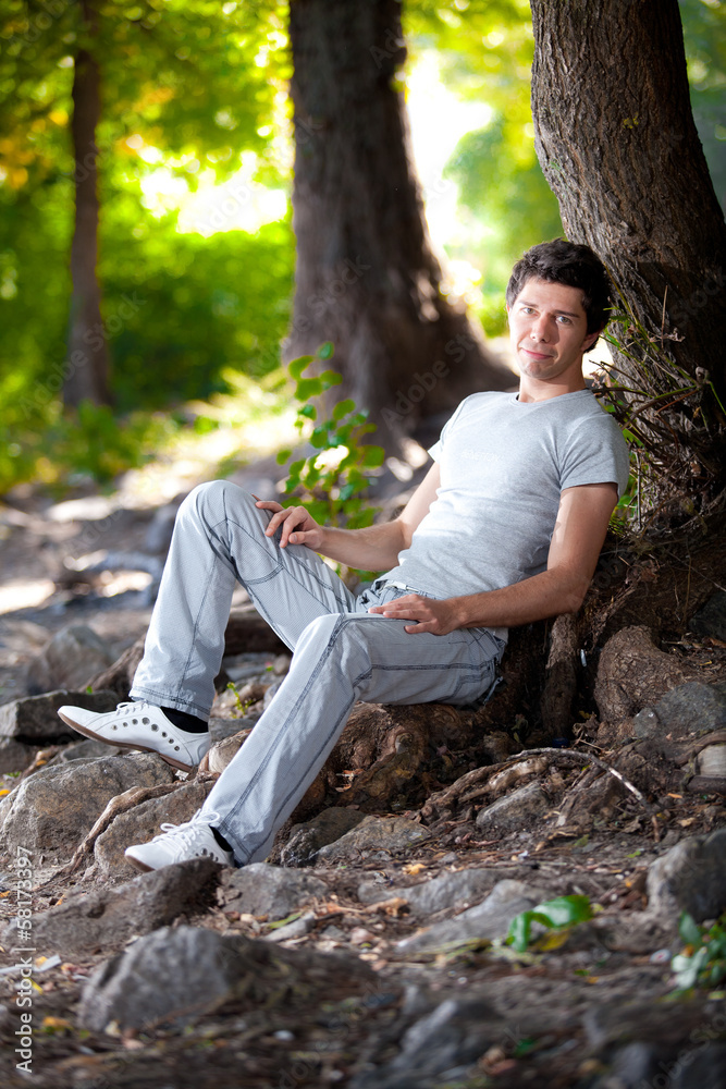 Handsome man in white clothes lying under tree in park Handsome man in white clothes lying under tree in park