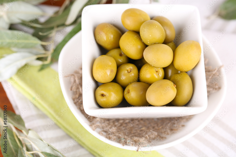 Olives in bowl with branch on napkin close-up Olives in bowl with branch on napkin close-up