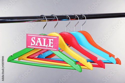 Wooden clothes hangers as sale symbol on gray background