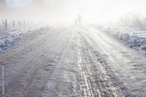 Mother and child on foggy snow farm road