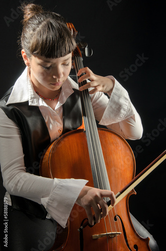 Girl with cello on black background