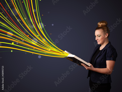 Pretty young woman reading a book while colorful lines are comin photo