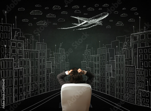 Businessman sitting in front of a cityscape drawing on a chalkbo