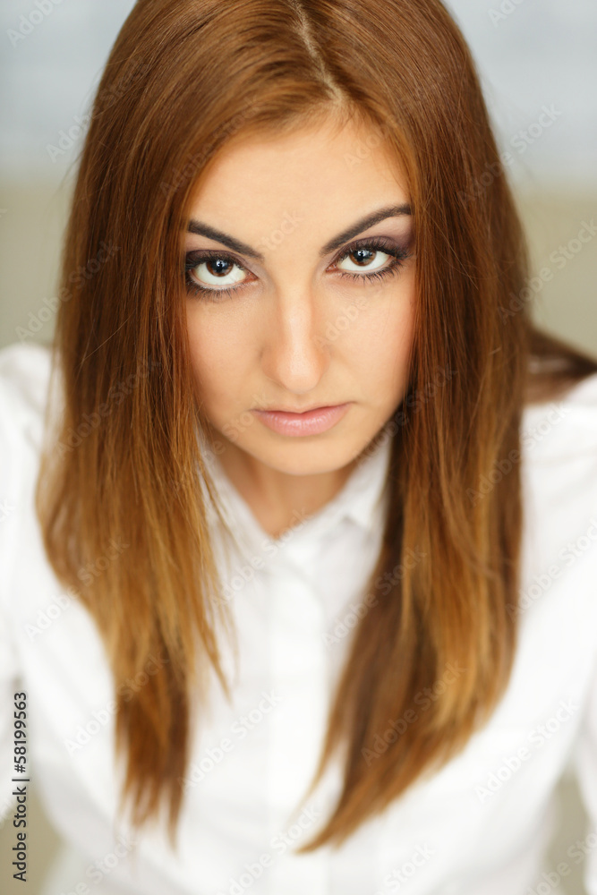 Young serious businesswoman sitting at the table in office Young serious businesswoman sitting at the table in office