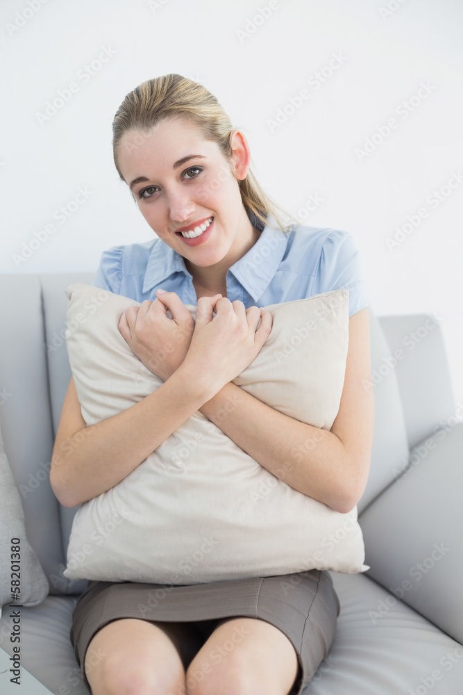 Cute chic businesswoman holding a pillow sitting on couch