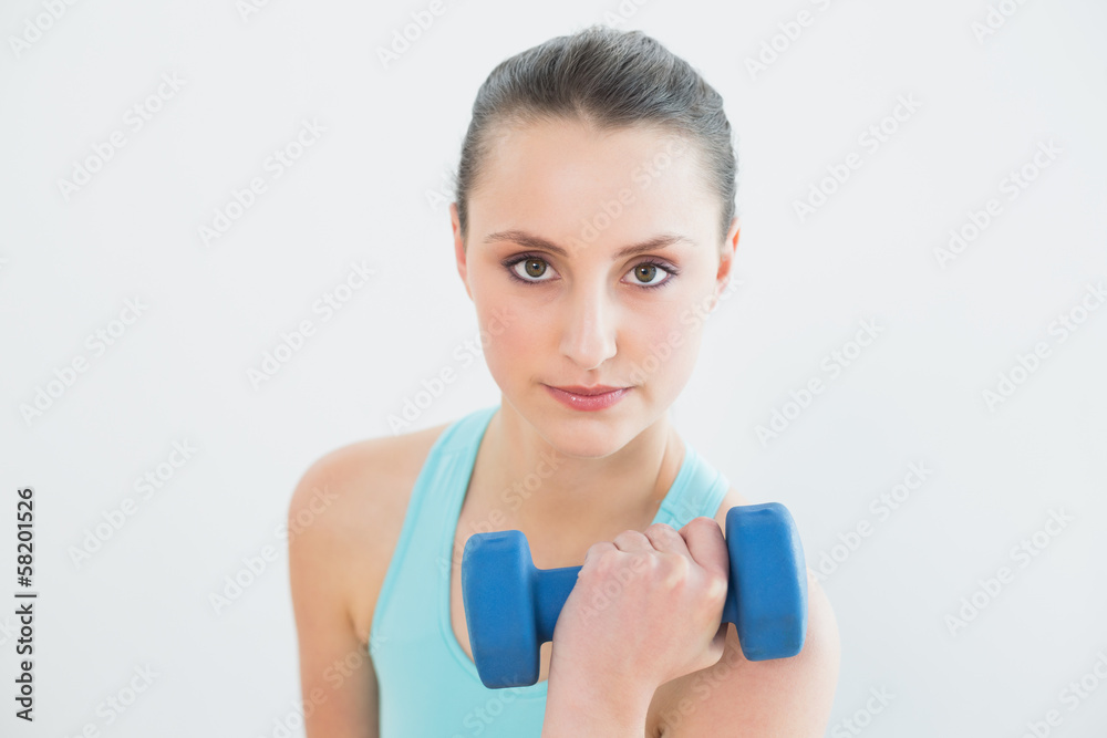Portrait of woman with dumbbell against wall Portrait of woman with dumbbell against wall