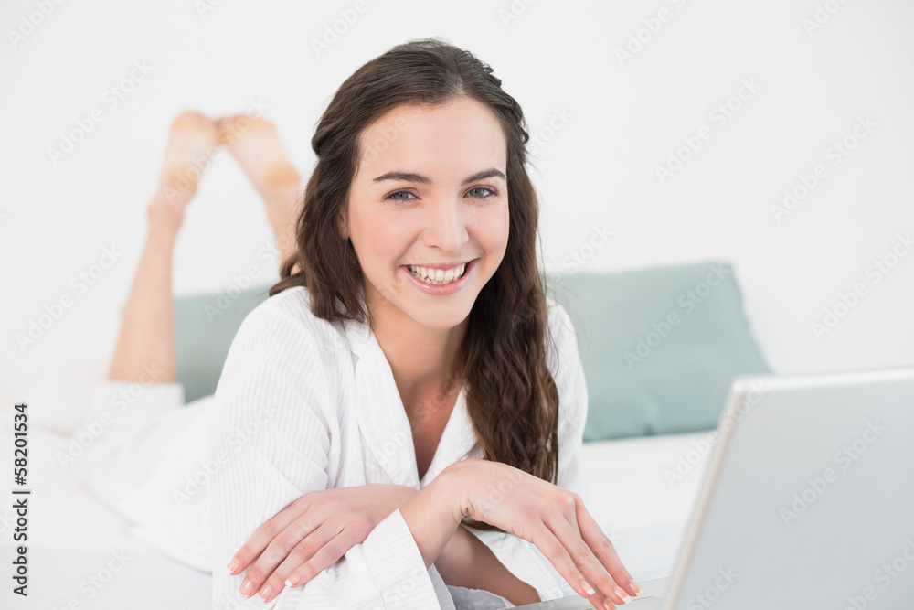 Relaxed smiling casual brunette with laptop in bed Relaxed smiling casual brunette with laptop in bed