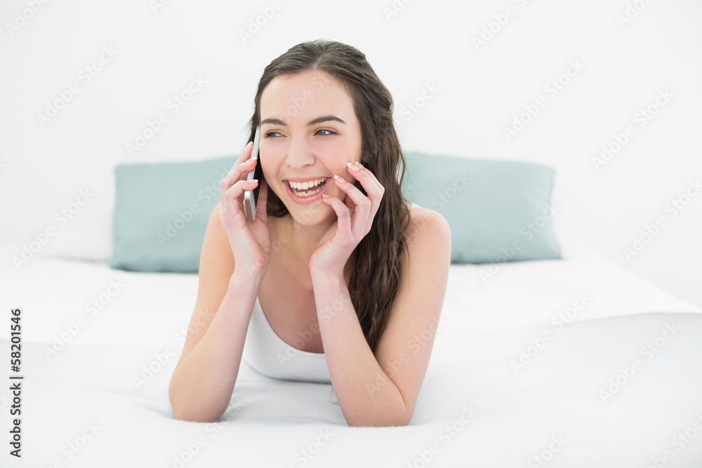Cheerful relaxed woman using mobile phone in bed