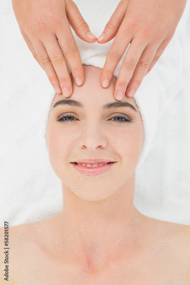 Hands massaging woman's forehead at beauty spa