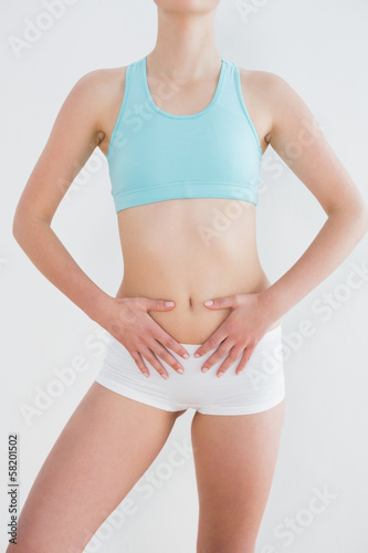 Fototapeta Naklejka Na Ścianę i Meble -  Mid section of a fit woman with hands on belly