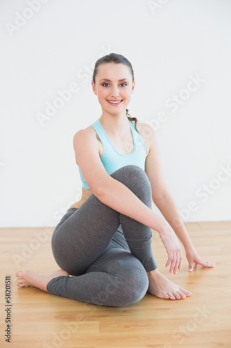 Fit woman sitting in cowface posture in fitness studio photo