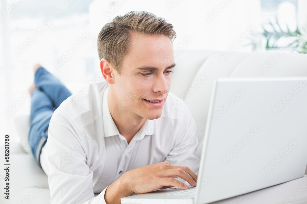 Relaxed casual man using laptop while lying on sofa Relaxed casual man using laptop while lying on sofa