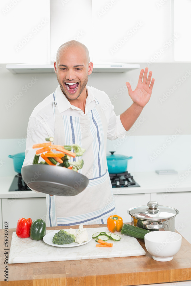 Cheerful man tossing vegetables in the kitchen Cheerful man tossing vegetables in the kitchen