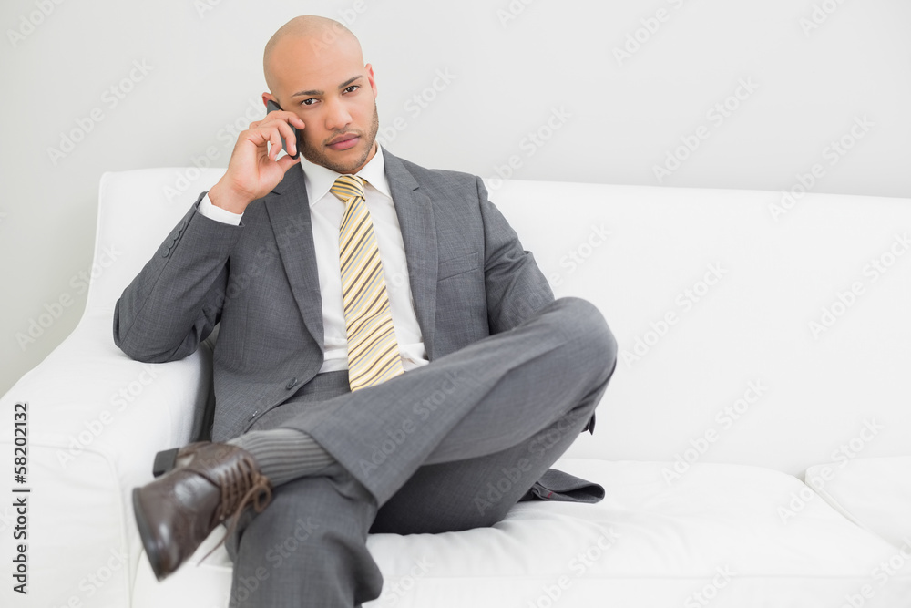 Businessman using cellphone on sofa at home Businessman using cellphone on sofa at home