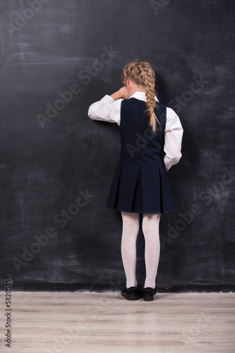 schoolgirl leaning her forehead against blackboard © alexsokolov