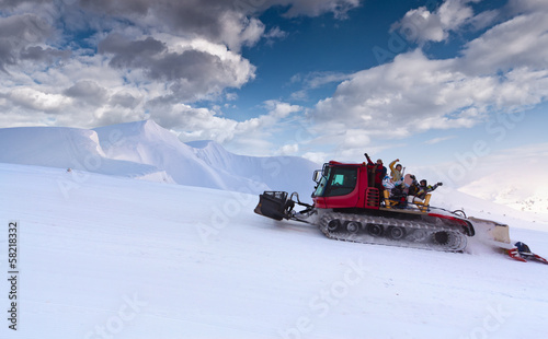 Snowcat with people going up the hill.