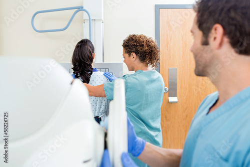 Nurse Adjusting Xray Machine In Examination Room