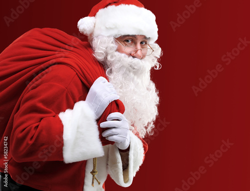 Portrait of Santa Claus carrying huge red sack with presents