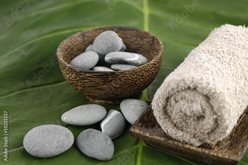 towel in bowl and zen stones in bowl on green leaf photo