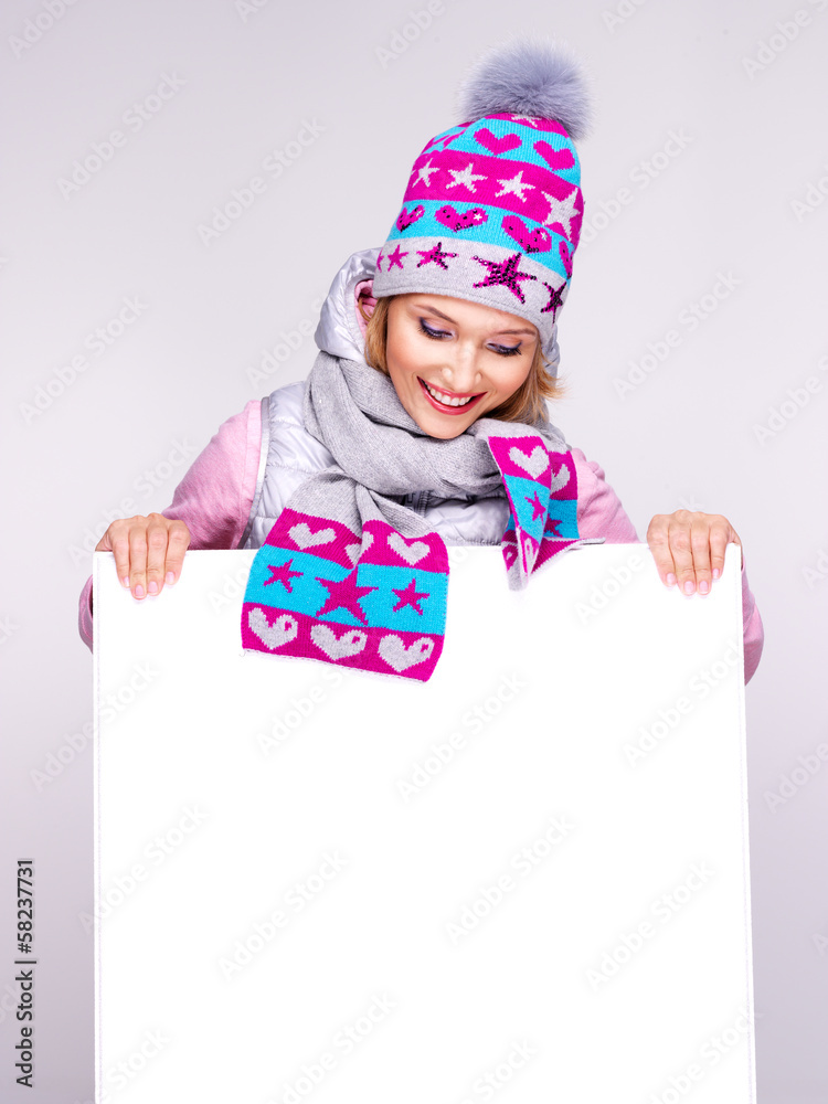 Adult smiling woman in winter hat holds the white banner Adult smiling woman in winter hat holds the white banner