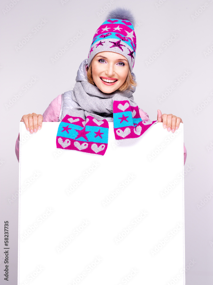 Adult smiling  woman in winter hat holds the white banner
