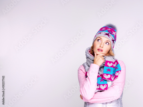 Photo of a thinking girl in winter clothes looking up