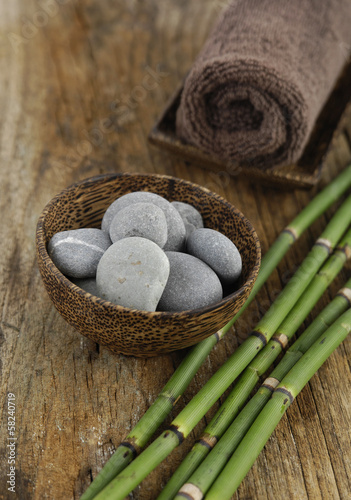 zen stones and towel in bowl and thin bamboo grove on mat