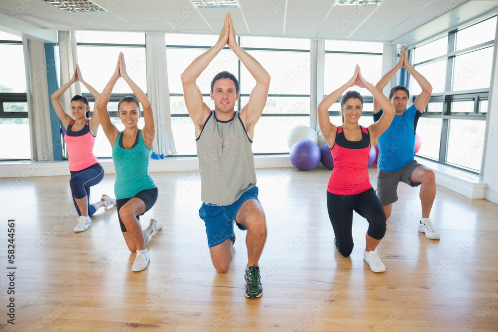 Obraz premium Fitness class and instructor kneeling in Namaste position